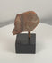 Rotating view of an ancient terracotta figural fragment showing a stylized face, painted ear ornament, surviving pigment traces, and archaeological surface details from multiple angles.