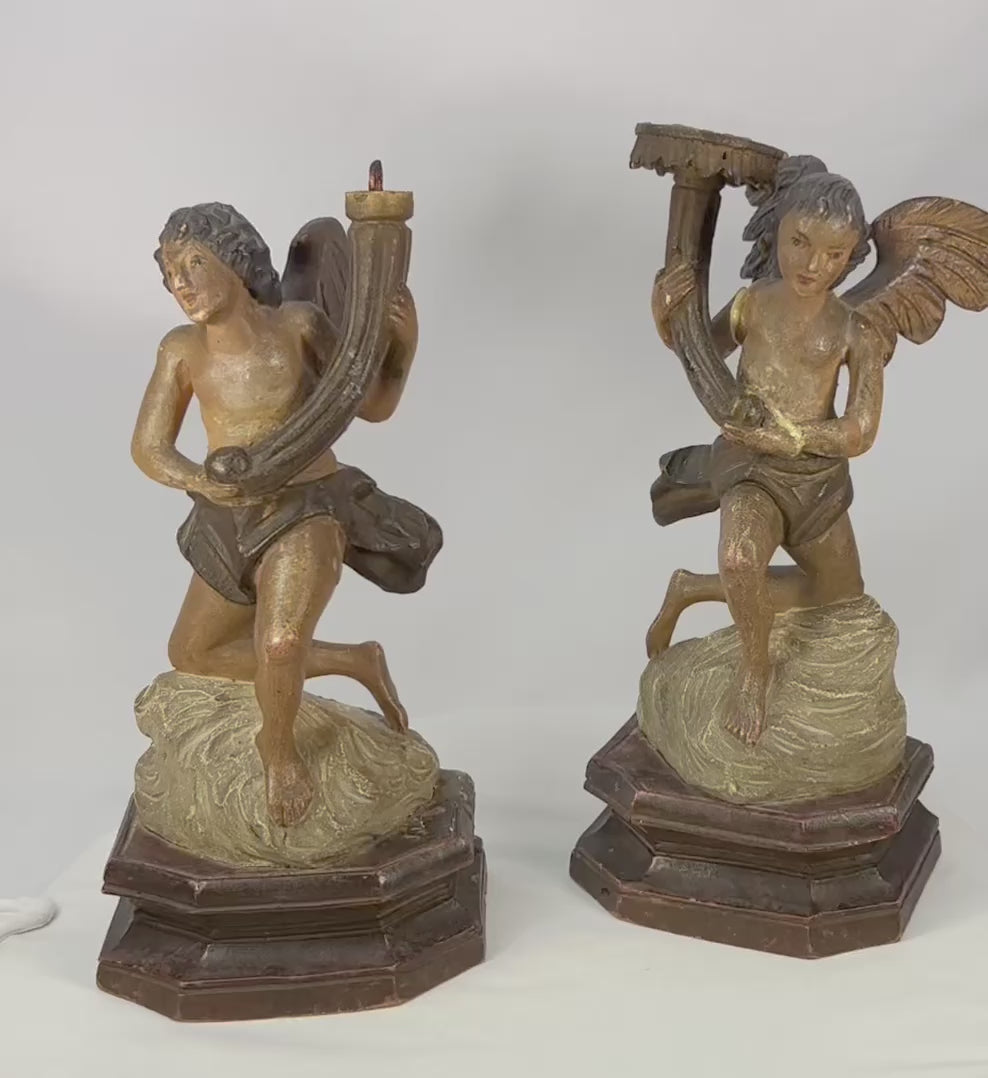360-degree view of a matched pair of antique carved wooden angel figures showing expressive faces, feathered wings, original polychrome and gilt traces, octagonal bases, and rich aged patina.