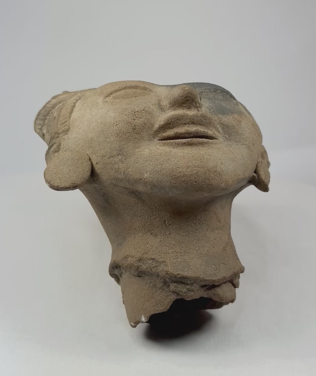 360-degree rotation of ancient terracotta head showing facial features and sculpted hair details.