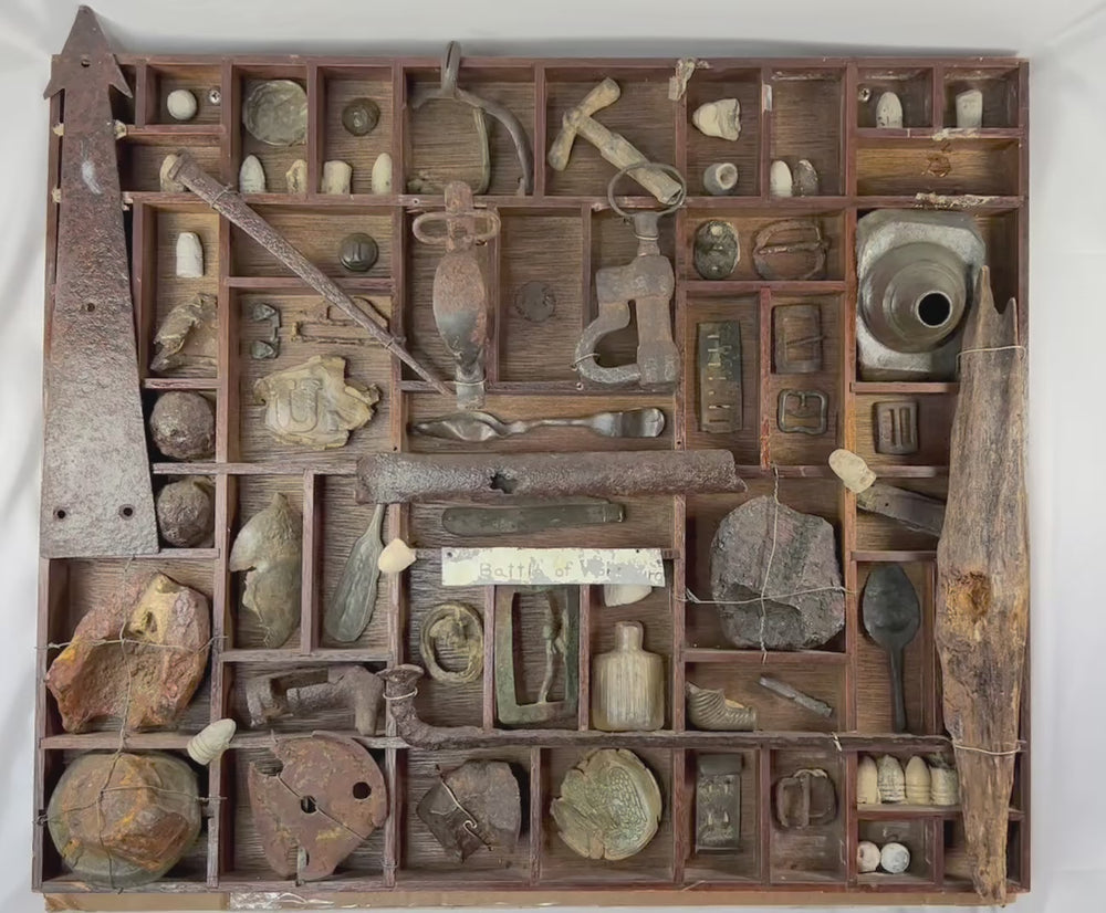 American Civil War shadow-box display of dug relics from the Battle of Vicksburg, Mississippi Valley, circa 1861–1865, featuring Minie balls, carved bullets, artillery and shell fragments, US plate and eagle breastplate pieces, spurs, stirrups, buckles, canteen spout, pipe bowl, glass bottle, camp hardware, all mounted in a wooden tray with wire supports and historic hand-written label