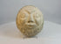 Rotating view of a hand-carved folk art stone face sculpture showcasing its expressive features and textured surface.