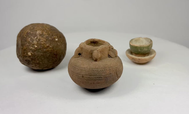 360-degree rotating view of three ancient Asian artifacts: a spherical stone tool, a miniature terracotta jar (ca. 500–1500 CE), and a green-glazed pedestal cup from the early 2nd millennium CE.