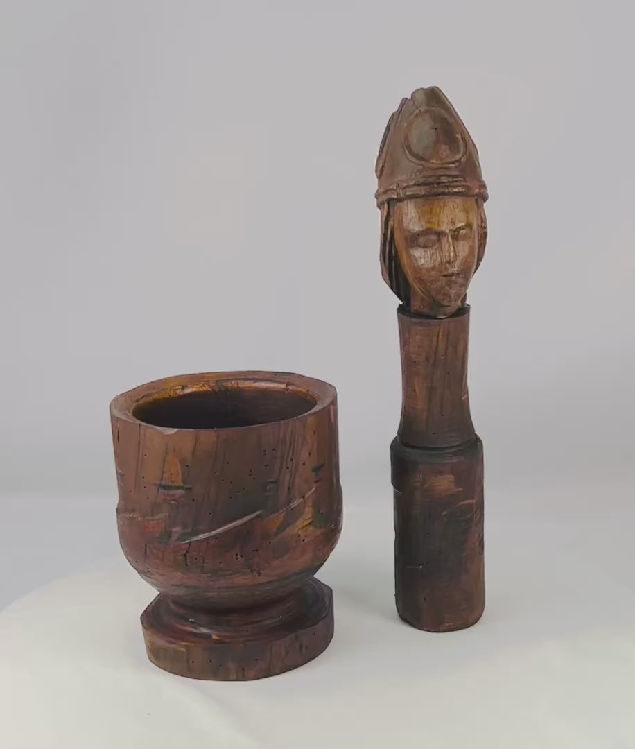 18th–19th Century European wooden mortar and pestle, featuring a finely carved human face on the pestle. The robust mortar and intricately detailed pestle showcase traditional craftsmanship, rich patina, and centuries of use, reflecting both utilitarian function and cultural artistry.