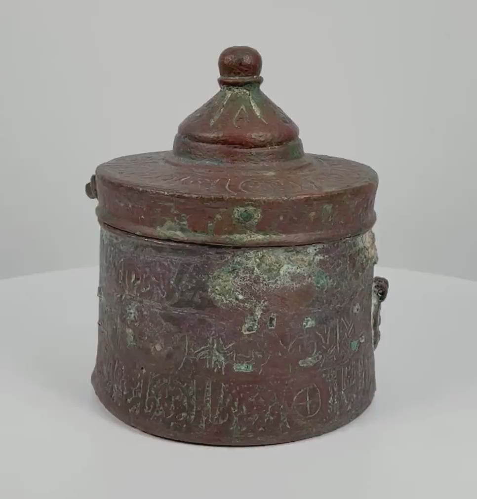 360-degree rotating video of an antique Islamic Khorasan bronze inkwell dating to the 10th–12th century CE, featuring intricate engraved floral and geometric motifs, traditional Islamic metalwork, and a rich natural bronze patina. A historical writing instrument from the Islamic Golden Age, showcasing its decorative craftsmanship and age-related surface details from multiple angles.