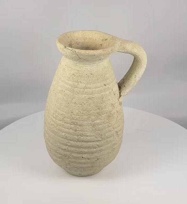 Ancient Roman North African terracotta pitcher from modern Tunisia displayed in a rotating 360-degree view, highlighting its rounded body, ribbed decoration, recessed neck, broad flaring rim, loop handle, archaeological patina, and Roman Imperial craftsmanship.