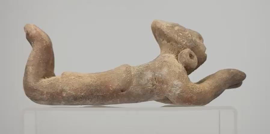 Video showcasing a Pre-Columbian-style terracotta prone human figure associated with coastal Ecuadorian sculptural traditions, highlighting its oversized rounded head, pierced circular earspools, extended arms, raised bent legs, reddish-brown earthenware surface, and weathered sculptural details.