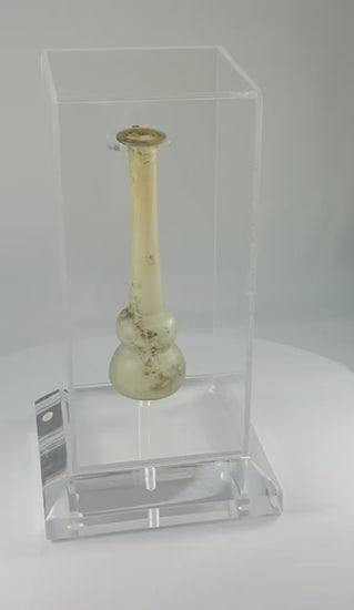 Ancient Roman clear glass double gourd balsamarium from the Eastern Mediterranean, 2nd–3rd Century CE. Features two globular sections joined by a slender neck, naturally iridescent patina, and substantial size for holding perfumes or balms. Reflects Roman glassmaking sophistication, luxury, and daily bathhouse culture.