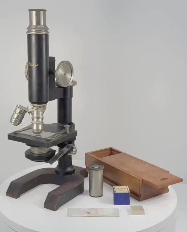 360-degree rotating view of an antique Spencer Lens Company compound monocular microscope, circa 1910–1920, featuring a black enamelled body, nickel-plated brass fittings, triple-objective nosepiece, precision focusing wheels, and horseshoe-shaped base. Accompanied by its original-style wooden carrying cabinet, glass slides, and scientific accessories.