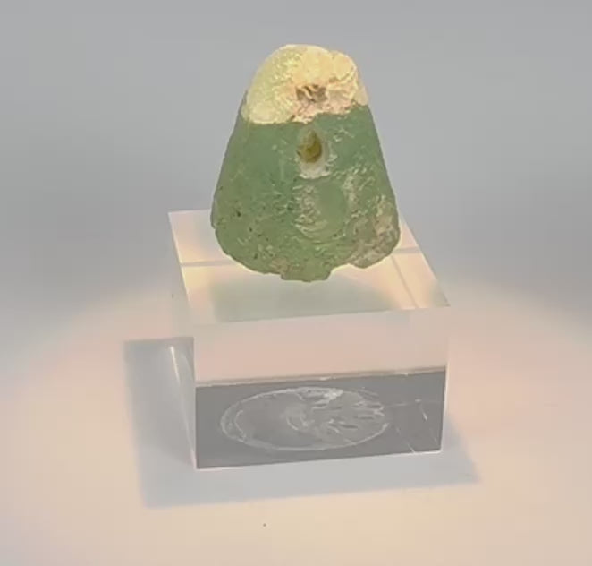 Rotating view of an ancient Near Eastern blue-green glass stamp seal with a rounded gumdrop-shaped body, transverse suspension hole, engraved sealing face reportedly depicting two rearing ibex flanking a central tree, pale mineral encrustation, surface weathering, localized iridescence, and a small fracture near the top
