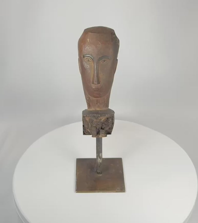 Rotating view of a Southeast Asian carved hardwood ceremonial figure fragment displaying expressive stylized facial features, weathered aged wood surface, traces of pigment, and mounted presentation on a custom metal display stand.
