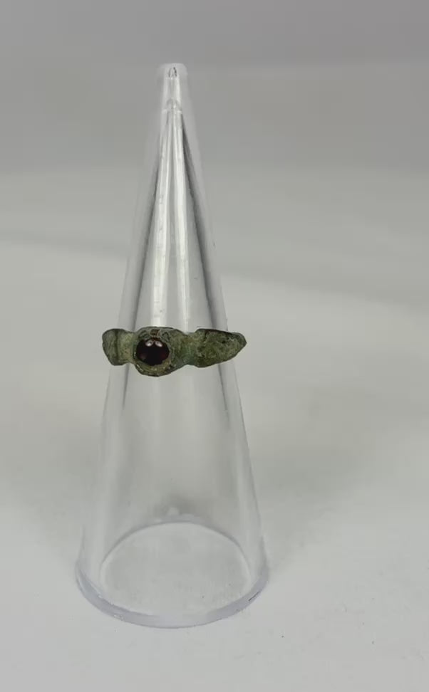Rotating video of an ancient Roman bronze ring with a deep red garnet gemstone.