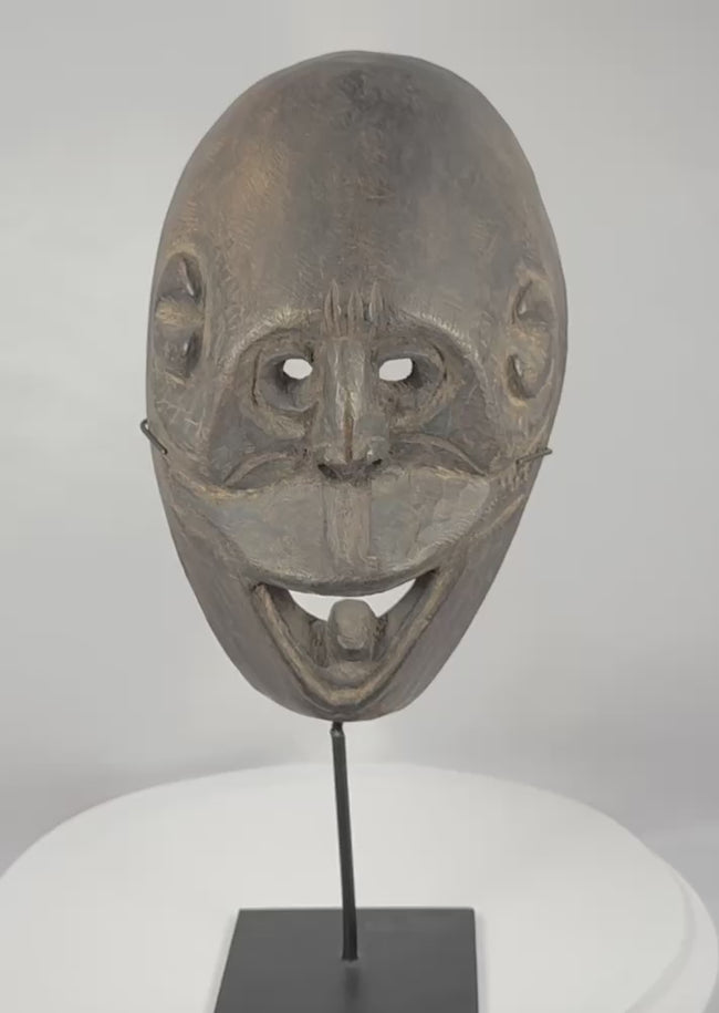 Rotating video of a West Timor ritual mask from Fatuleu Village, circa 1930, displaying traditional Atoni carving traditions, large pierced eyes, an open mouth with protruding tongue, and an aged hardwood surface.
