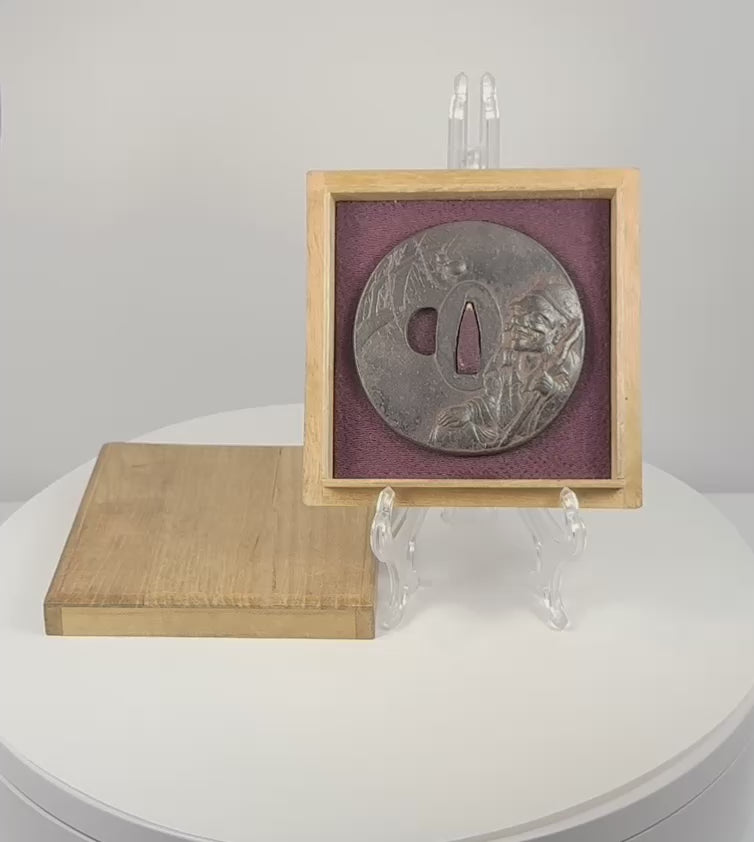 Rotating view of an antique Japanese iron tsuba with mixed-metal sage and spider decoration, displayed in its purple-lined wooden box