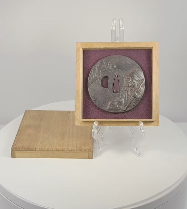 Rotating view of an antique Japanese iron tsuba with mixed-metal sage and spider decoration, displayed in its purple-lined wooden box