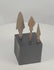 Rotating view of three ancient Roman to medieval hand-forged iron projectile points, including an elongated point with pronounced shoulders, a broad leaf-shaped point, and a narrow triangular arrowhead, each with a surviving tang, heavy oxidation, mineral encrustation, and an individual black display base