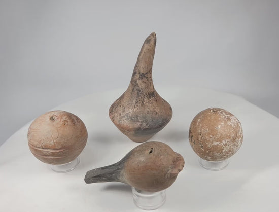 Rotating view of four authentic Pre-Columbian terracotta ritual rattles with hollow sound chambers, mineral patina, and archaeological wear, circa 300 BCE–900 CE.