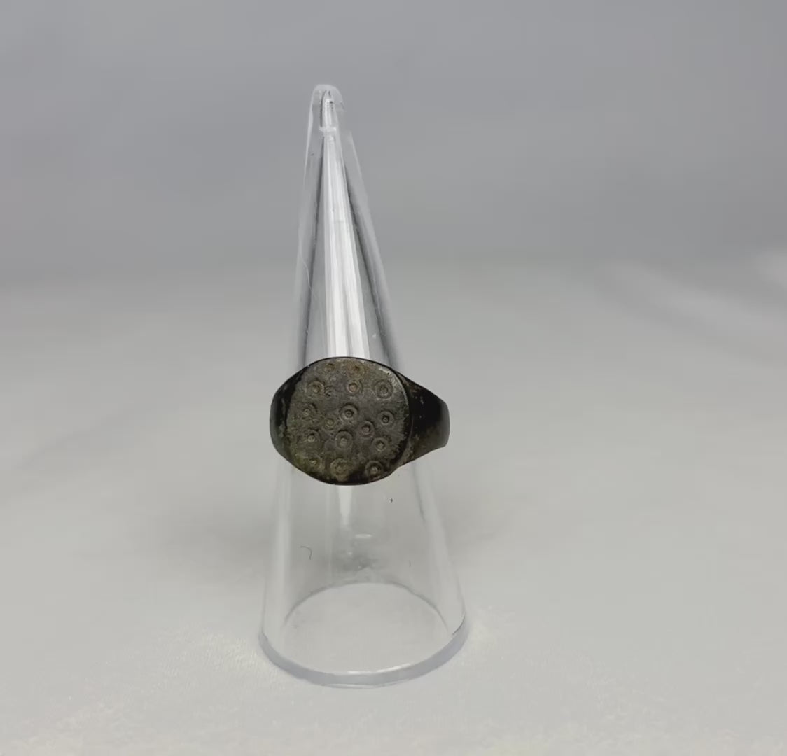 Ancient Roman bronze ring, size 7 US, featuring a flat bezel engraved with irregular “ring and dot” motifs symbolizing the sun, with authentic patina and well-preserved surface from the 1st–3rd century CE.