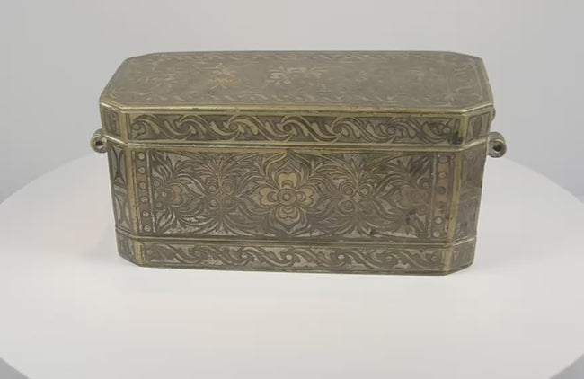 Rotating 360-degree video of an antique Philippine betel nut box, circa 1780–1820, showing its brass-inlaid exterior, engraved floral decoration, side rings, and fitted interior compartments.