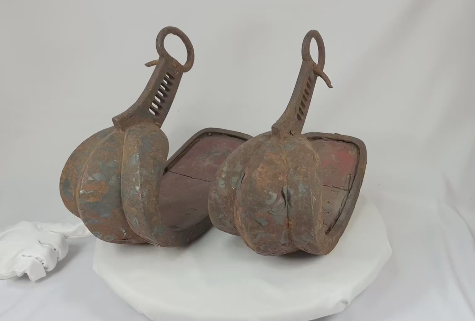 Matched pair of late 18th–mid-19th-century Japanese abumi stirrups with hand-forged iron, broad scooped treads, triple-lobed toe guards, red interior lacquer, black/brown exterior lacquer remnants with painted scrollwork, large suspension rings, Edo period, circa 1770–1860.