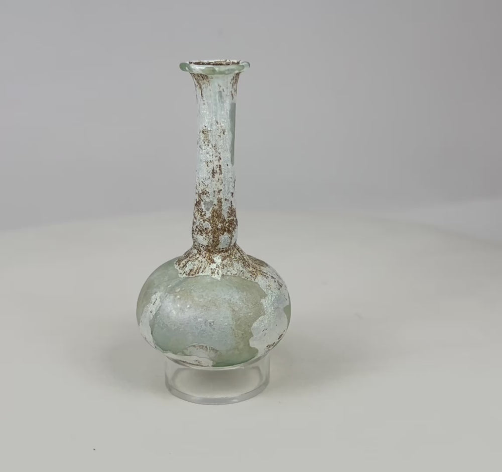 360° rotation of Roman glass bottle showing pale green color, iridescent surface, and flared rim.