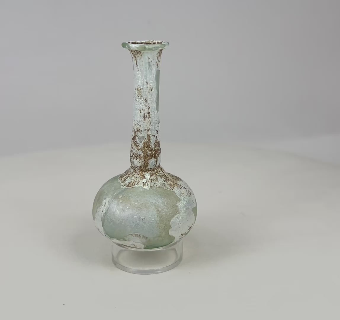 360° rotation of Roman glass bottle showing pale green color, iridescent surface, and flared rim.