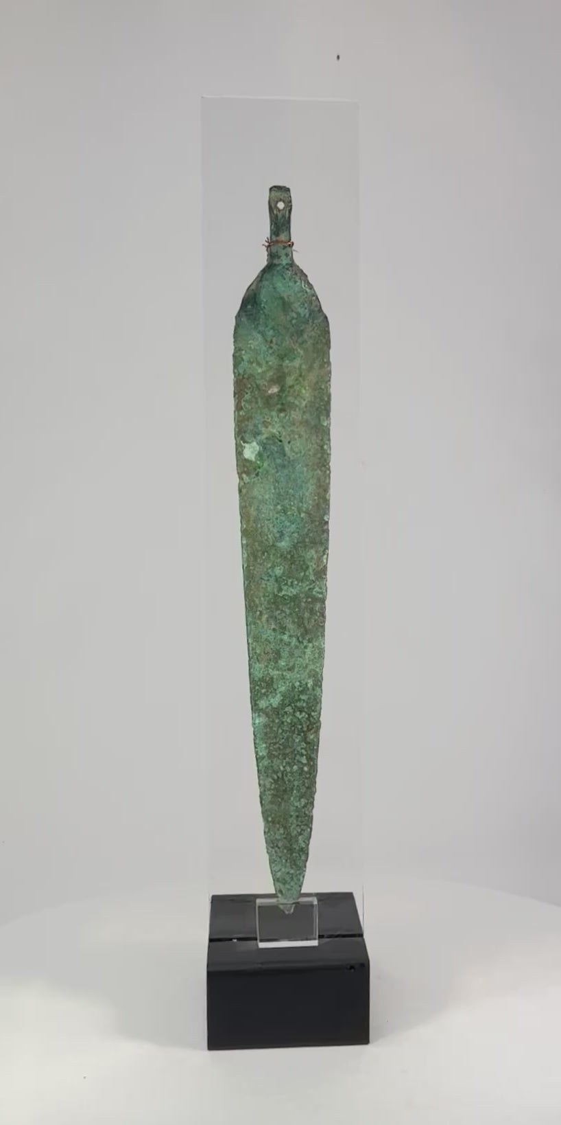 Ancient Western Asiatic bronze dagger blade, 1st millennium BCE, with tapered form, central spine, perforated base, and green patina.