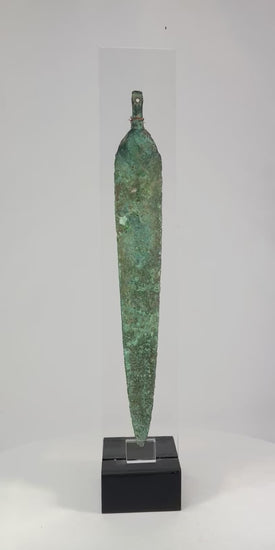 Ancient Western Asiatic bronze dagger blade, 1st millennium BCE, with tapered form, central spine, perforated base, and green patina.