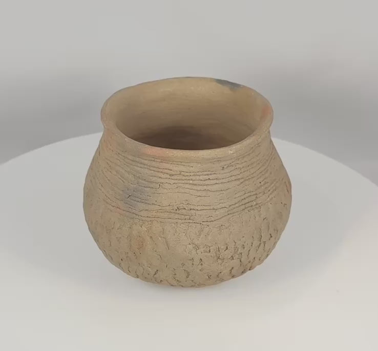 Rotating view of an authentic Pre-Columbian Casas Grandes corrugated pottery jar from northern Mexico, highlighting its hand-built earthenware construction, textured surface, corrugated shoulder bands, archaeological patina, and ancient utilitarian form.
