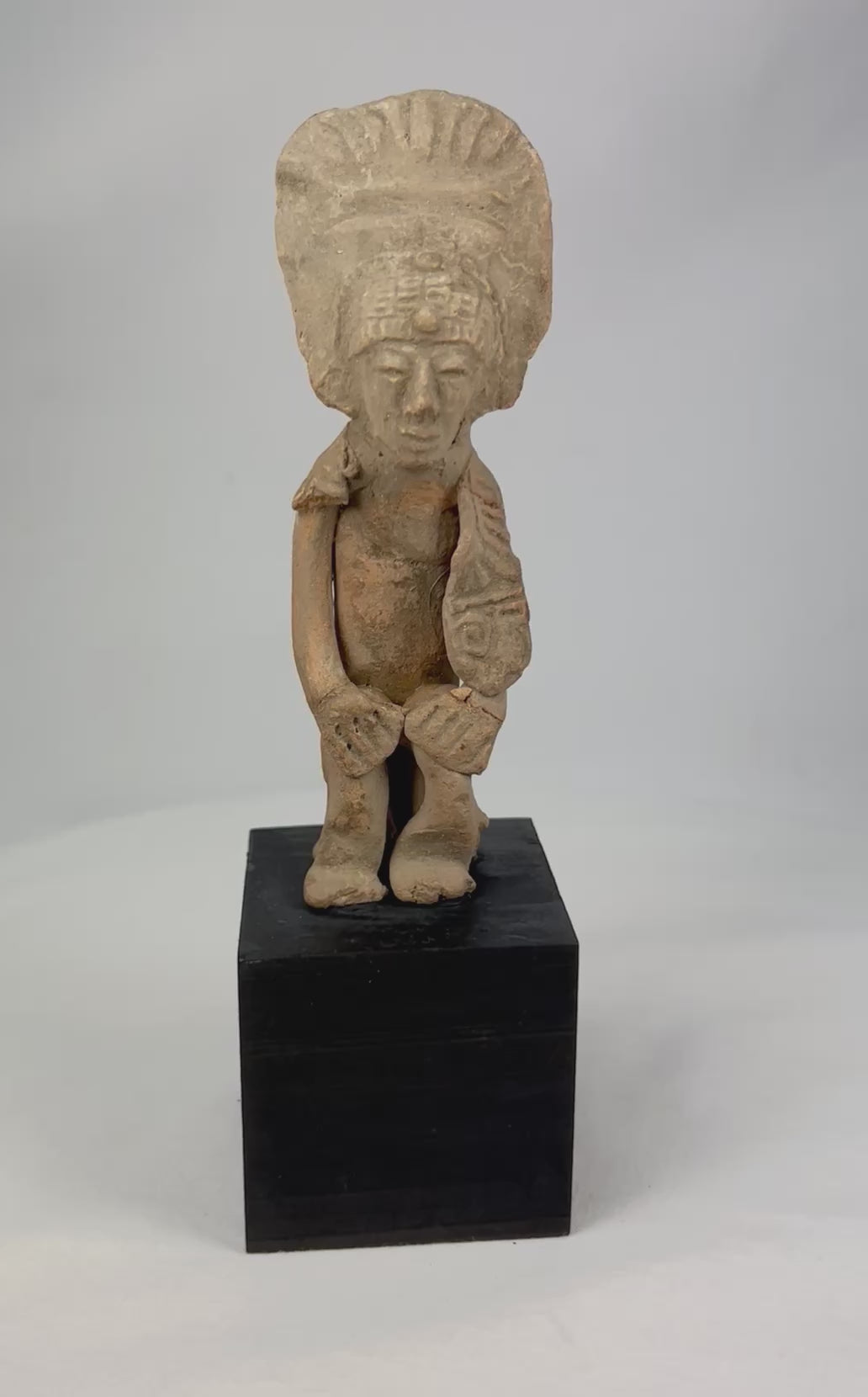 Pre-Columbian West Mexican terracotta standing figure, 300 BCE–500 CE, Nayarit or Jalisco shaft tomb culture, with tall radiating headdress, abstract geometric features, and mineral accretions, mounted on display base