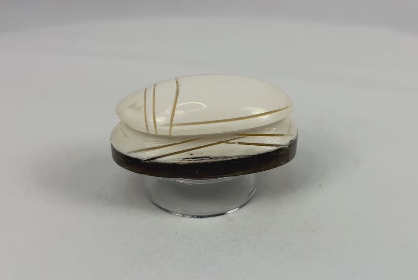 Rotating video of an East Asian hand-carved scarab-form talisman displayed on a dark oval base.