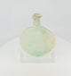 360-degree view of an ancient Roman free-blown pale green glass flask with flattened circular body, elongated neck, burial encrustation, iridescence, and historic repairs displayed on a clear acrylic stand.