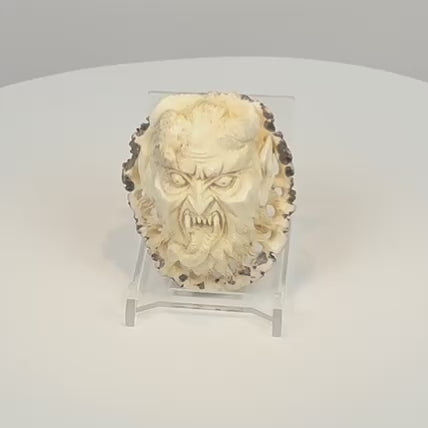 Rotating view of an antique Japanese stag antler oni demon face carving, showing its deep-relief features, openwork edges, and porous reverse.