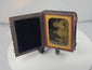 Rotating view of a quarter-plate Victorian Rehn ambrotype depicting three female sitters in period dress, housed behind a gilt brass mat in its original velvet-lined leatherette case