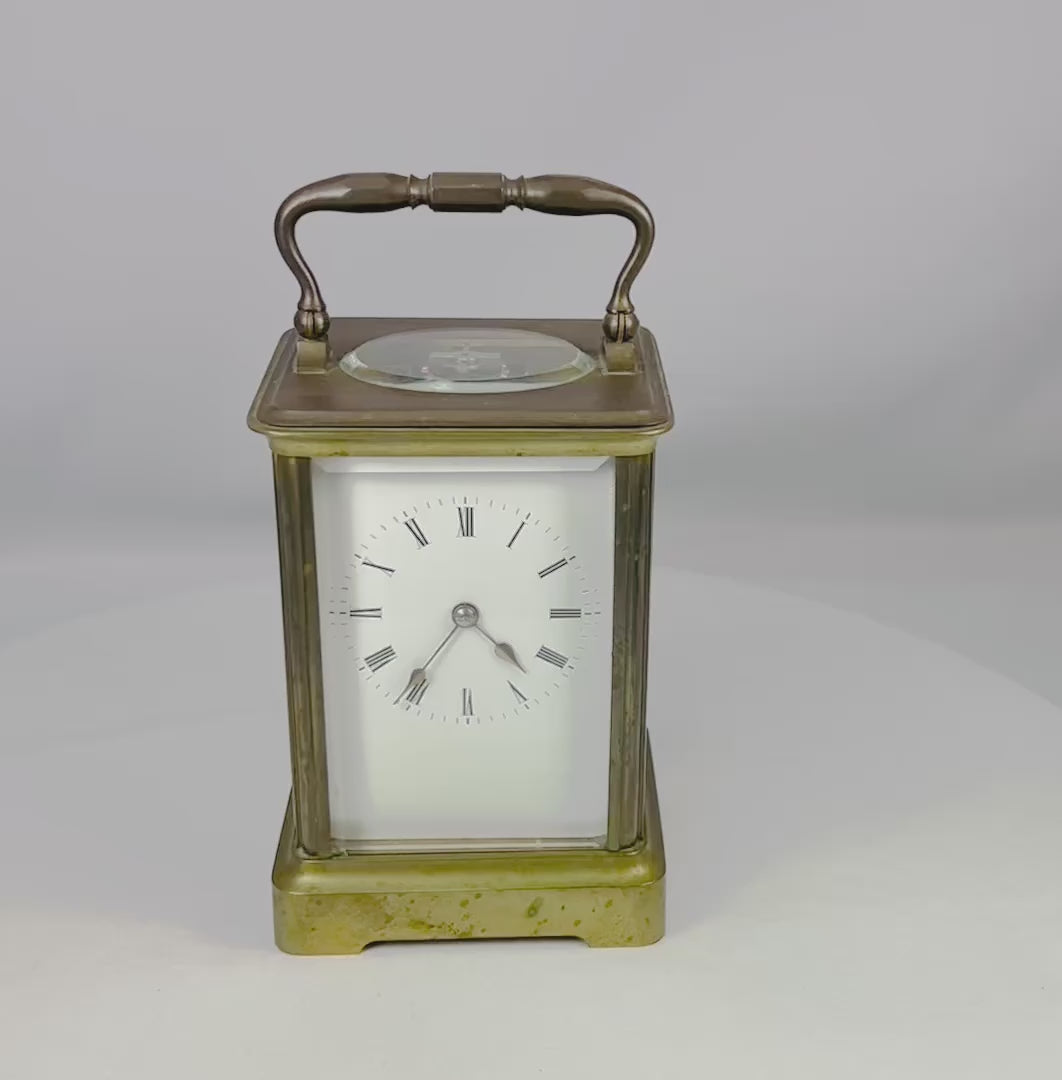 Elegant antique French brass carriage clock with beveled glass panels, white enamel dial with Roman numerals, and visible escapement through the top panel, stamped with a “B” in a circle attributed to Jules Bunelot, circa late 19th century.
