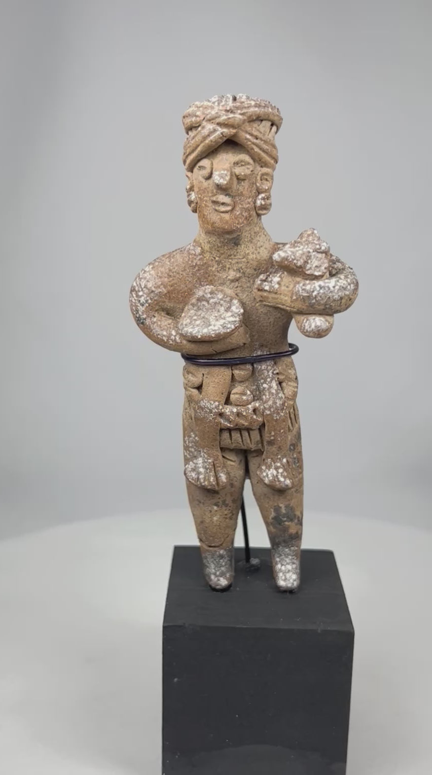 Ancient West Mexican Pre-Columbian standing terracotta figure rotating on display, showing headdress, body adornments, stylized features, and mineral encrustations.