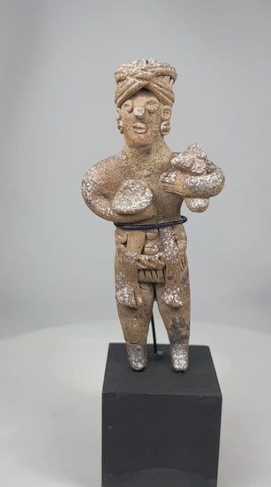 Ancient West Mexican Pre-Columbian standing terracotta figure rotating on display, showing headdress, body adornments, stylized features, and mineral encrustations.