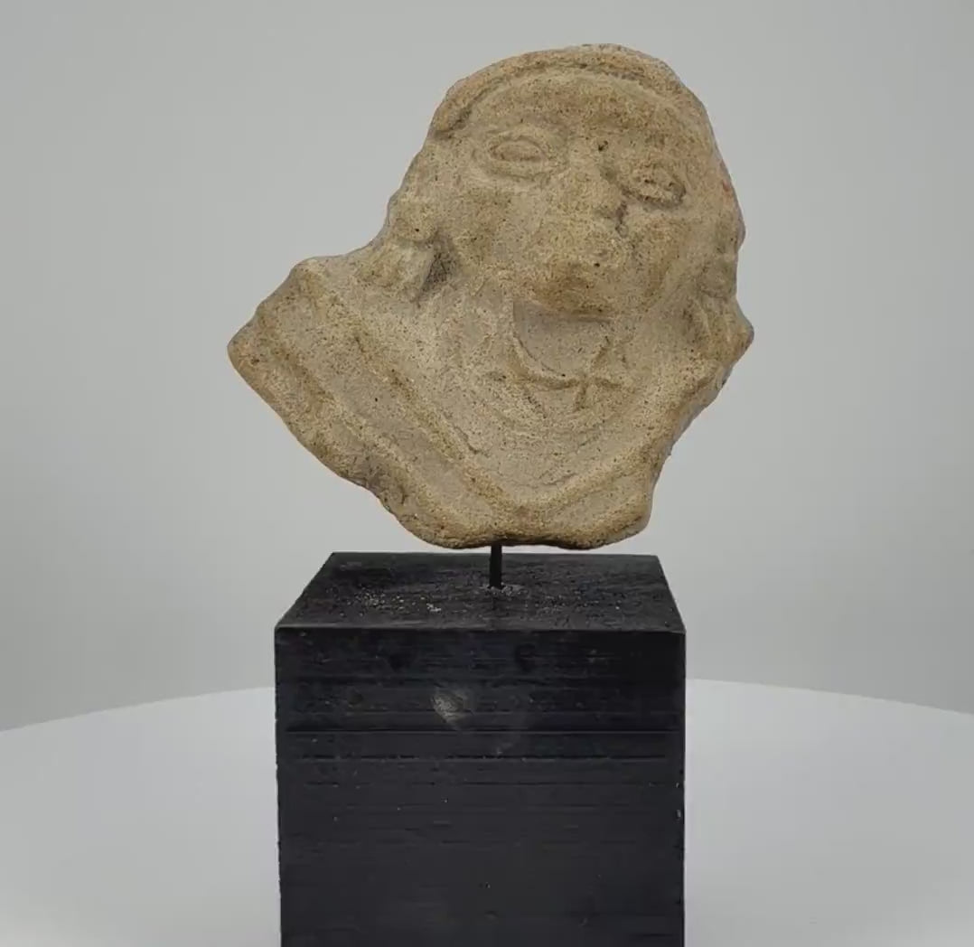 360-degree rotating video of an ancient terracotta female figure fragment featuring stylized facial features, prominent eyes, detailed hair, and decorative clothing. Attributed to West Mexico (Nayarit/Jalisco) or the Iberian Peninsula, circa 200 BCE–300 CE.