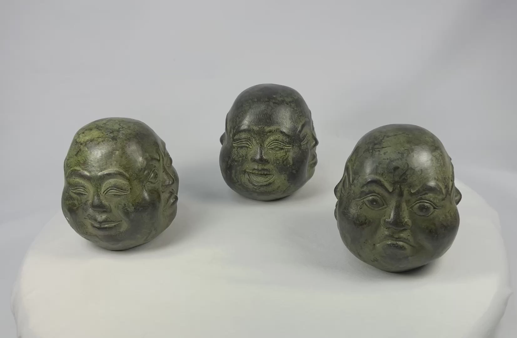 20th century Himalayan cast metal Buddha heads, sand-filled, patinated bronze finish, set of three in traditional brocade box, devotional and ritual meditation objects