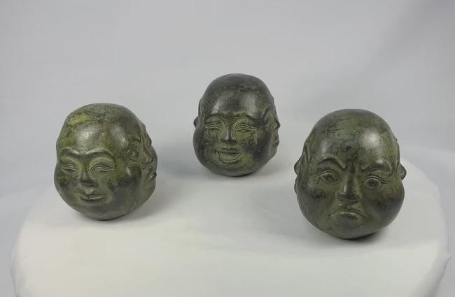 Rotating video of a set of three sand-filled cast metal Buddhist heads with green patina presented in brocade box, Himalayan region, 20th century