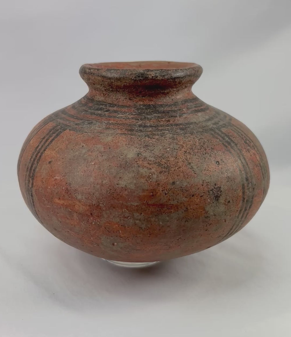 360-degree view of an authentic West African terracotta vessel showing its rounded form, black painted geometric decoration, warm earthen surface tone, and natural aging patina.