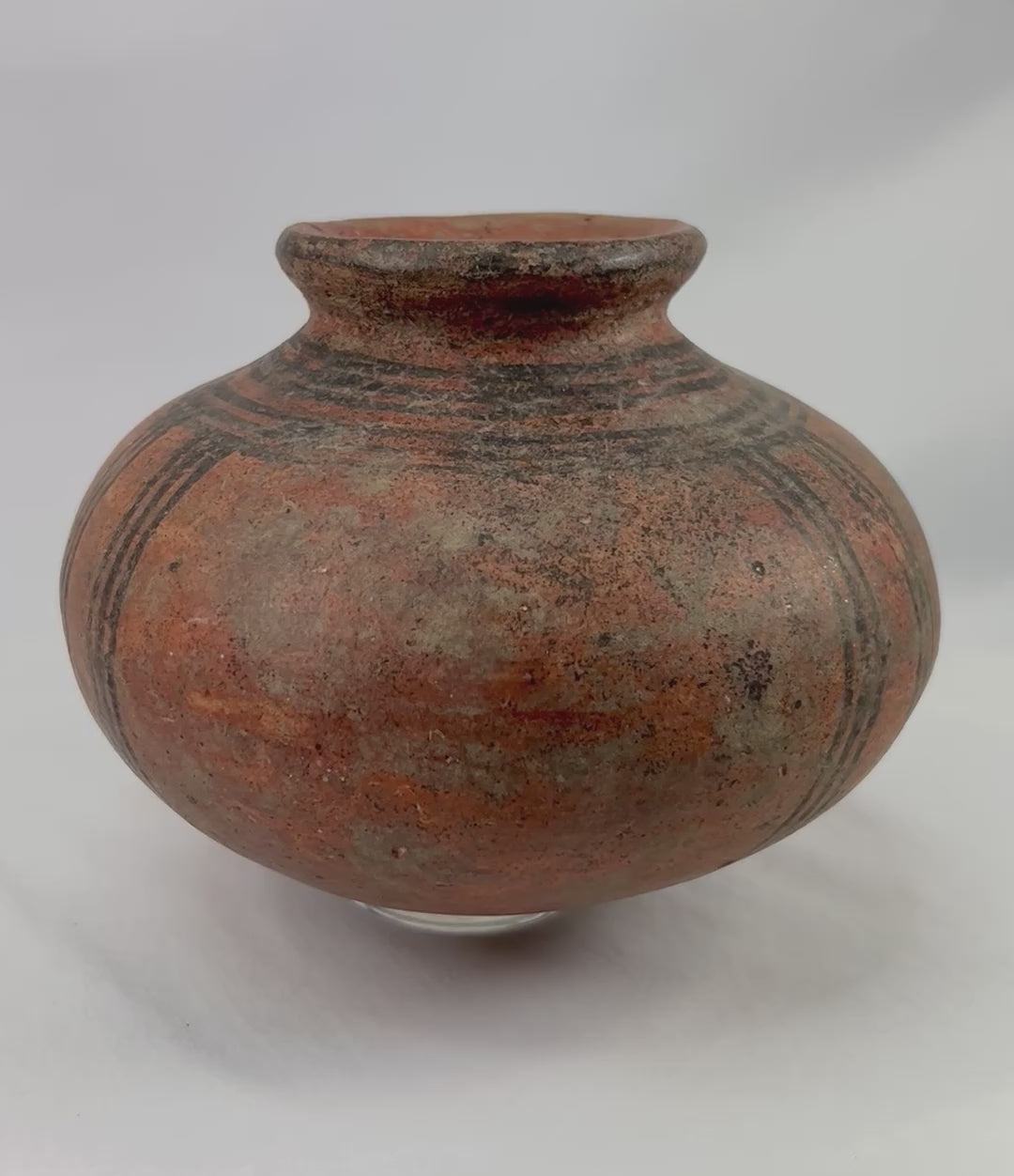 360-degree view of an authentic West African terracotta vessel showing its rounded form, black painted geometric decoration, warm earthen surface tone, and natural aging patina.
