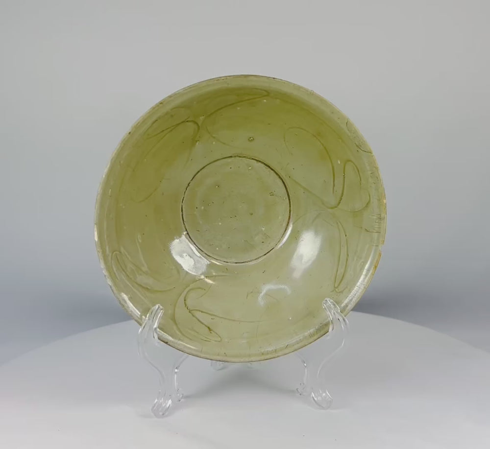 12th-Century Song Dynasty celadon bowl rotating on display—light green glaze with incised floral decoration, Fujian ware recovered from the Jepara Shipwreck.