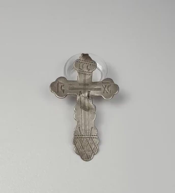 Video showcasing a late 19th-century Russian Orthodox silver pendant cross, highlighting its engraved Crucifixion imagery, scalloped terminals, traditional Orthodox inscriptions, aged silver patina, and 84 zolotnik hallmark on the reverse.