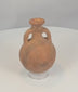 Rotating view of an ancient Cypriot Black-on-Red terracotta flask with a compact globular body, short neck, broad everted rim, opposing loop handles, orange-red slipped surface, black painted bands, flattened underside, mineral accretions, weathering, and archaeological patina