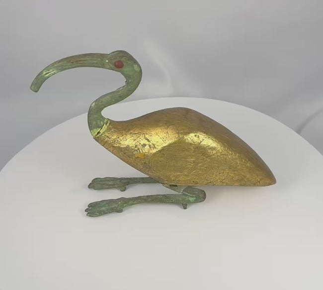 360-degree video of an Egyptian Revival sacred ibis sculpture featuring a gilt body, verdigris-patinated neck and legs, red inset eye, and elegant mixed-media construction, showcasing the sculpture from all angles.