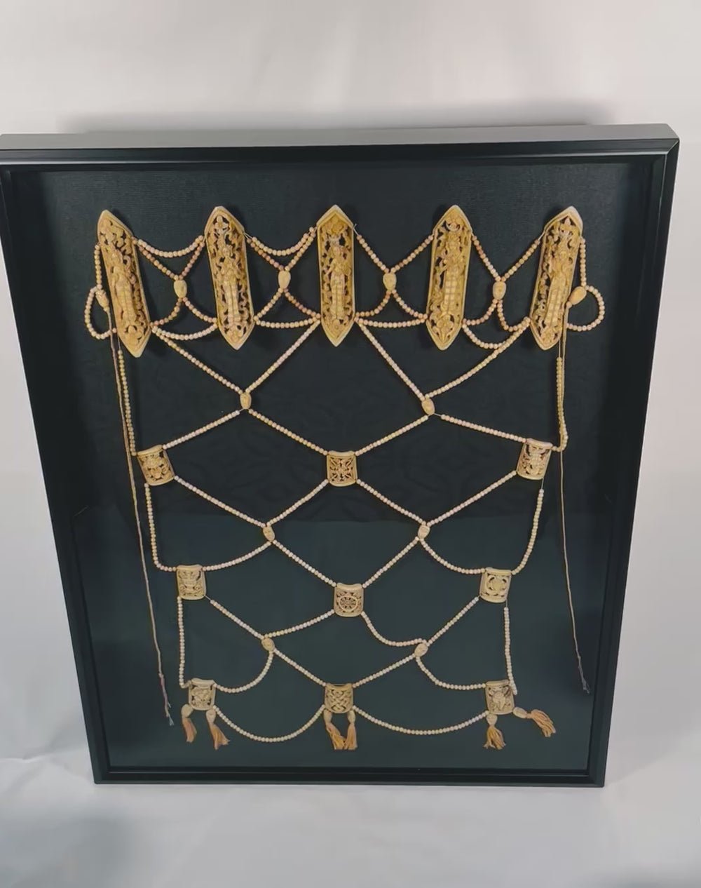 Tibetan Tantric Ritual Bone Apron (Rus Gyan) from 19th century Himalayas, carved human and animal bone plaques with deity figures displayed in museum-quality black frame — symbolic Buddhist artifact of impermanence and enlightenment.