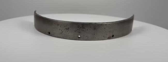 Antique 17th-century European forged steel armor band formerly held in the Higgins Armory Museum collection, featuring a thick curved structure, evenly spaced rivet holes, traditional hand-forged metalwork, natural aged patina, surface pitting, and historic wear characteristic of early modern European defensive armor.
