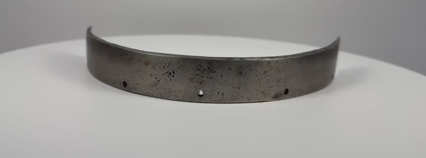 Antique 17th-century European forged steel armor band formerly held in the Higgins Armory Museum collection, featuring a thick curved structure, evenly spaced rivet holes, traditional hand-forged metalwork, natural aged patina, surface pitting, and historic wear characteristic of early modern European defensive armor.