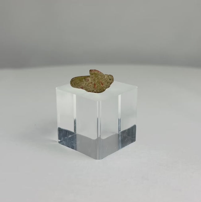 Ancient bronze ring with broad shield-shaped face and green-brown patina, shown rotating to reveal its form, surface texture, and archaeological wear.