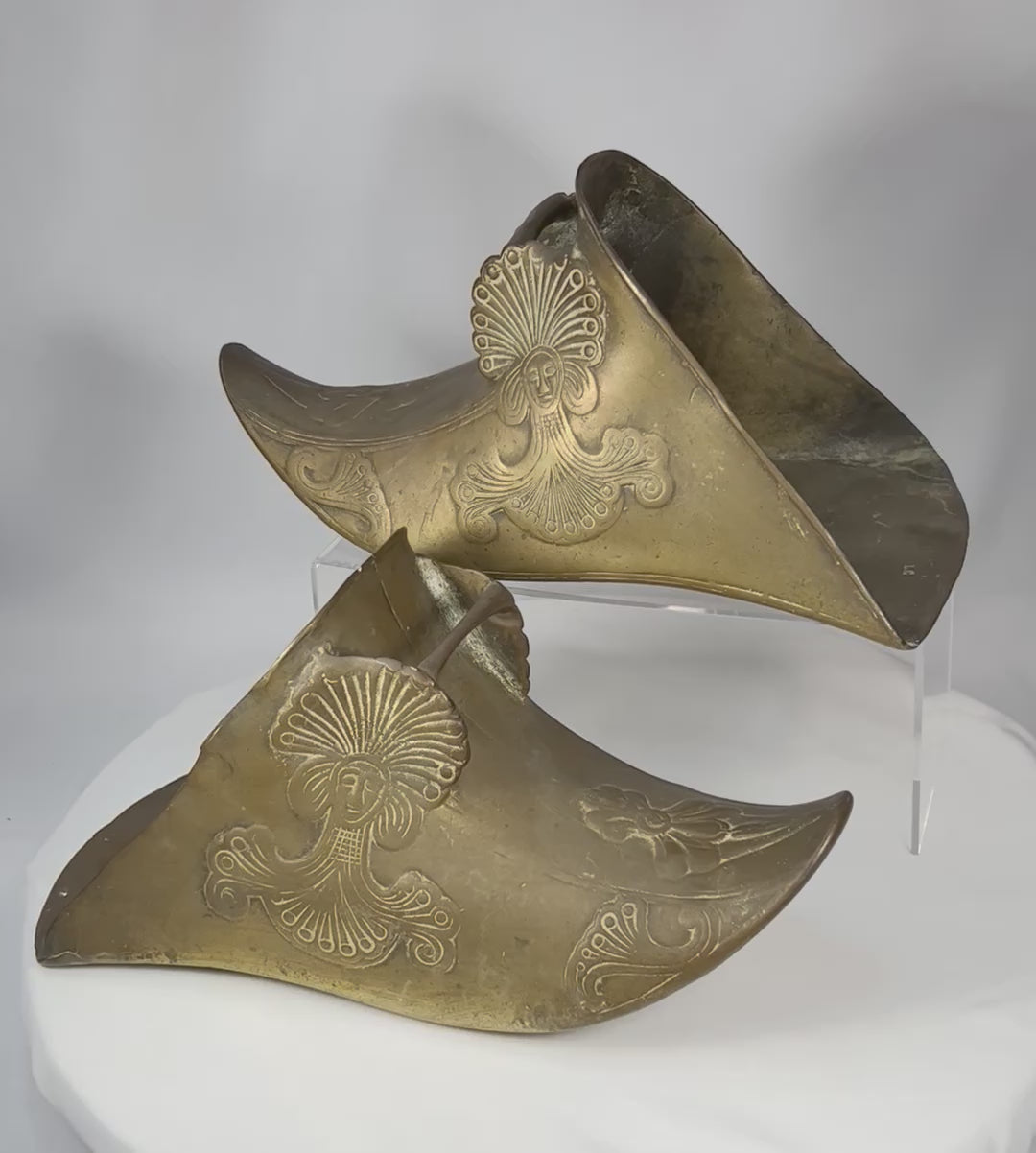 360-degree view of antique Spanish Colonial brass slipper stirrups showing enclosed riding form, relief decoration, and aged patinated surfaces.
